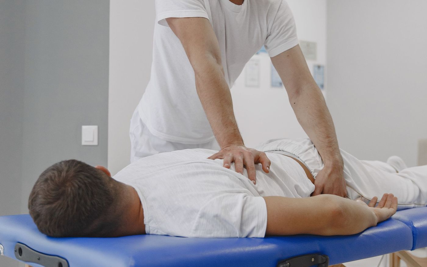 A chiropractor performing a hands-on spinal adjustment in a treatment room