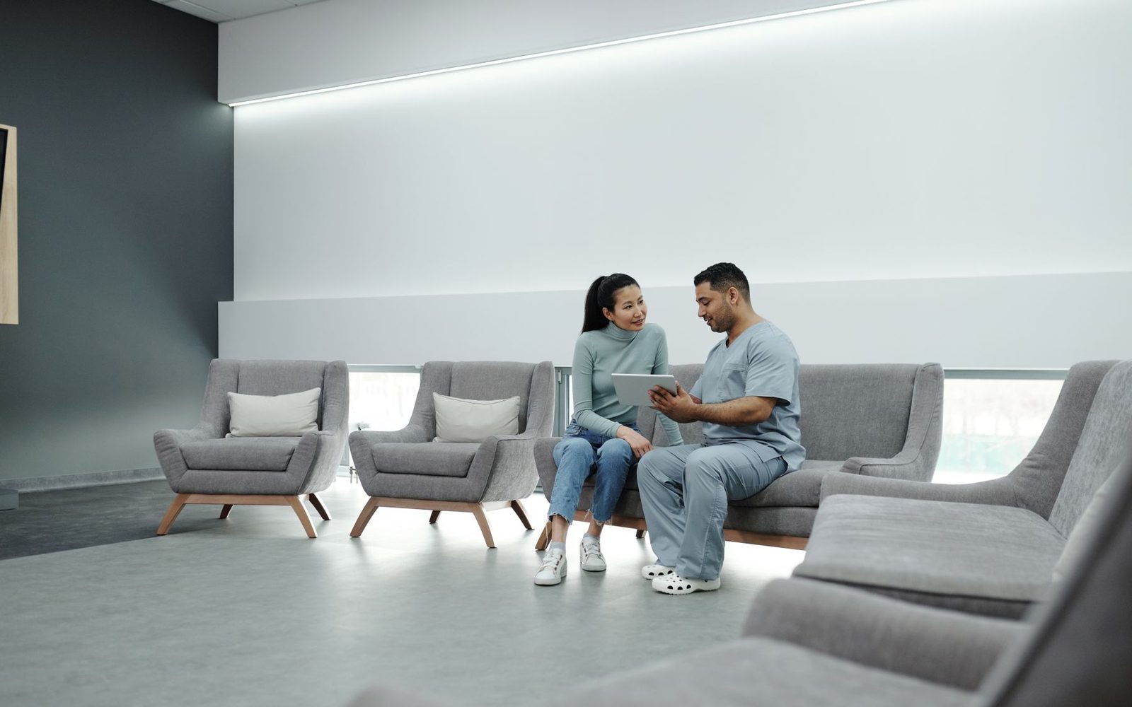Patients checking in at a modern chiropractic clinic waiting area