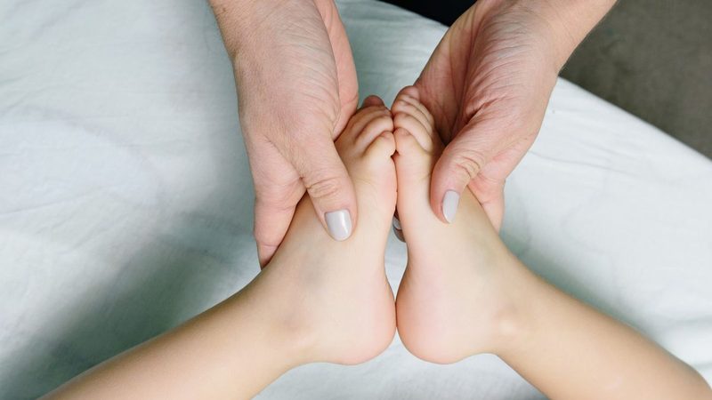 A parent gently holding a child's feet during a pediatric chiropractic visit