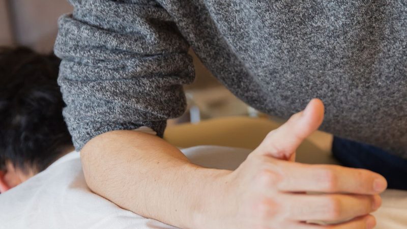 A clinician applying hands-on pressure to a patient's back